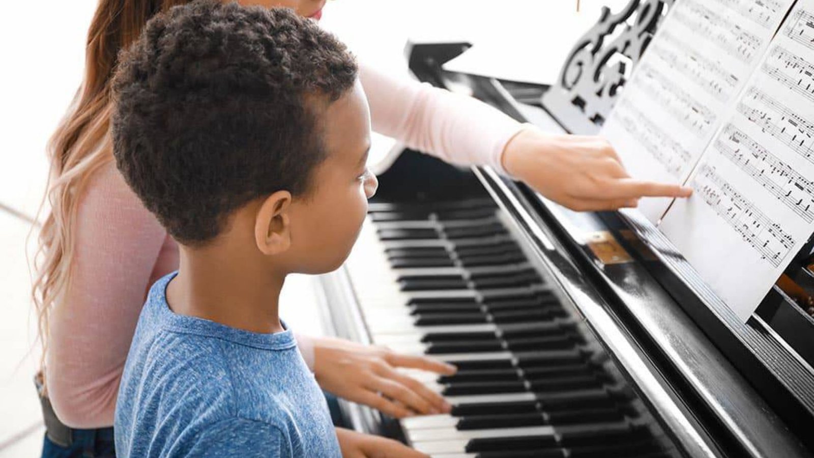a lady teaching a kid how to play a keyboard showing musical styles 
