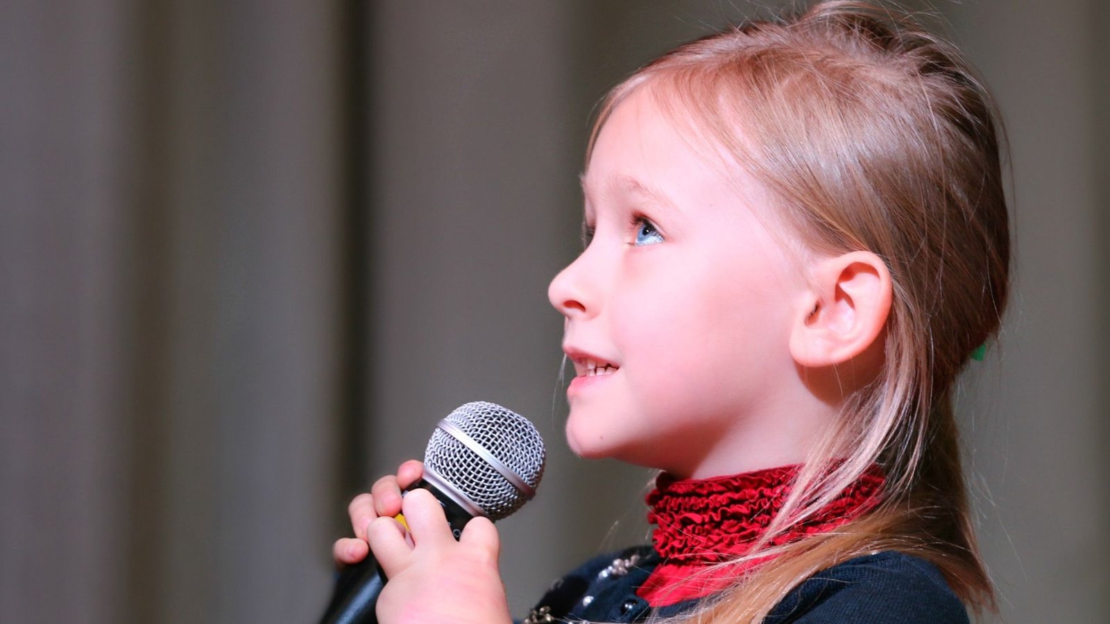 a small girl singing while holding a mic showing stage fright